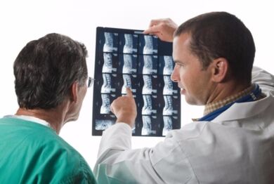 The doctor looks at the image of the spine